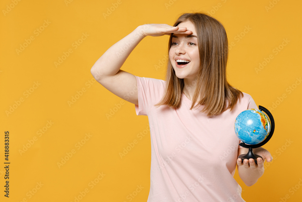 Young smiling happy woman 20s wearing casual basic pastel pink t-shirt holding in palms Earth world globe holding hand at forehead look far away distance isolated on yellow background studio portrait. Young smiling happy woman 20s wearing casual basic pastel pink t-shirt holding in palms Earth world globe holding hand at forehead look far away distance isolated on yellow background studio portrait.