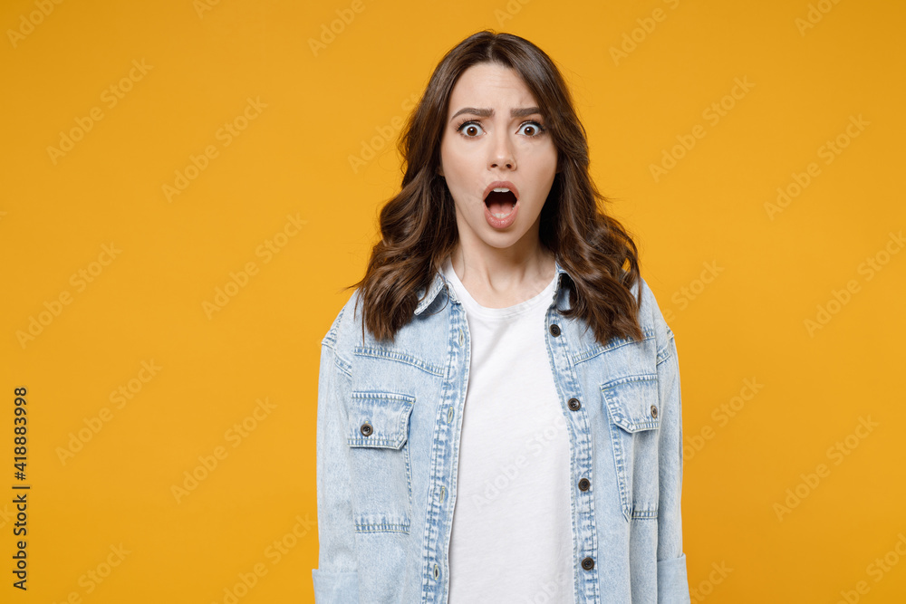Young shocked confused wondered astonished indignant woman 20s wearing stylish casual denim shirt white t-shirt looking camera with opened mouth isolated on yellow color background studio portrait Young shocked confused wondered astonished indignant woman 20s wearing stylish casual denim shirt white t-shirt looking camera with opened mouth isolated on yellow color background studio portrait