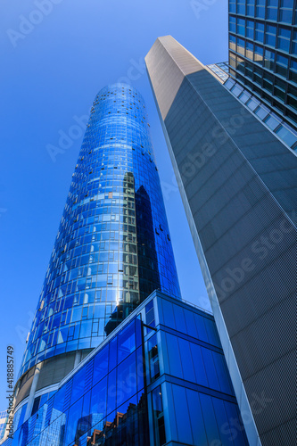 Skyscrapers and skyscrapers looking upwards. Window facade of commercial buildings in Frankfurt Main. Blue sky in sunny day. Reflections in the glass facade