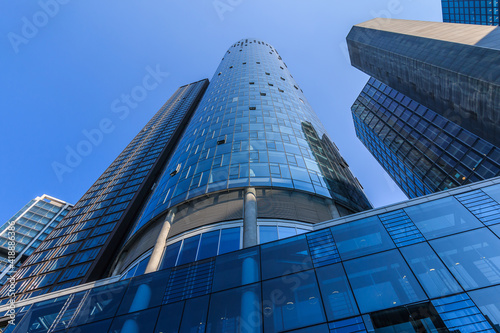 Buildings from the financial and business district in the center of the city. View along high-rise buildings with window facade in Frankfurt Main. Light reflections in sunshine and blue skies.