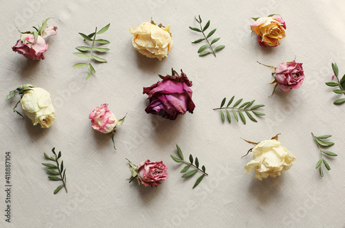 Fototapeta Naklejka Na Ścianę i Meble -  Dried roses and leaves arrangement on light linen background edited in warm instagram colors. floral patter. rustic style and country lifestyle. flat lay top view. international women day background 