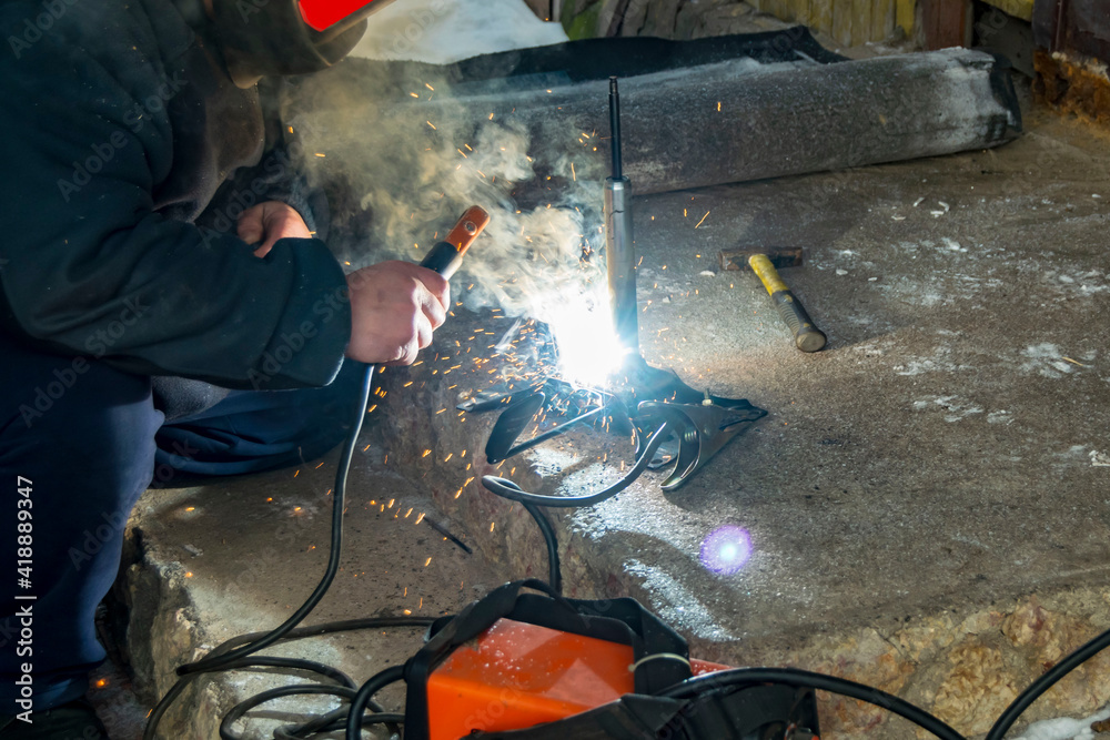 The man makes electric welding at home. The man makes electric welding at home.