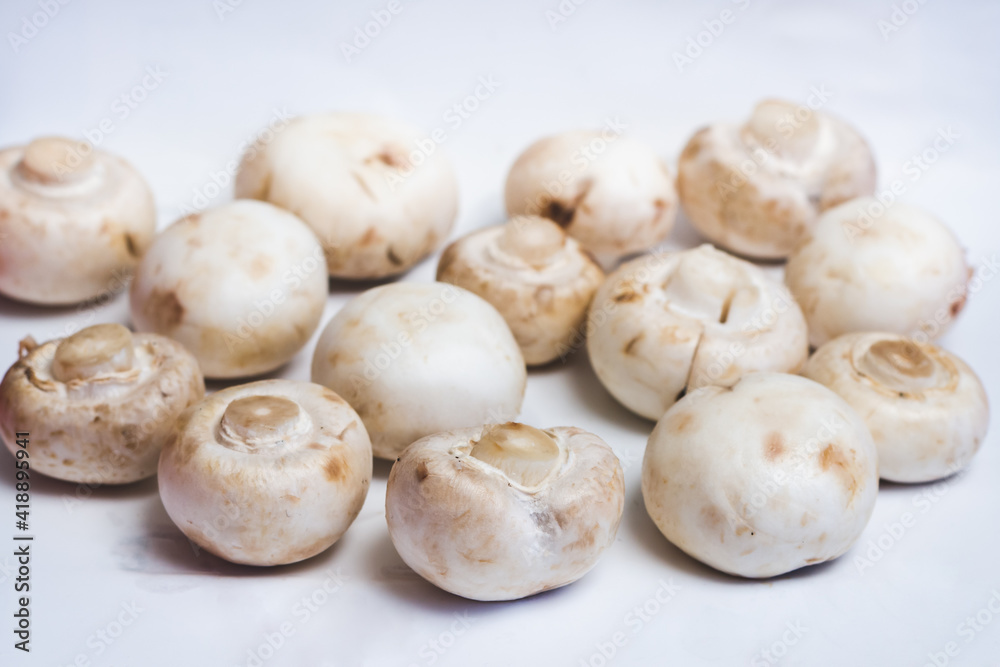 Young whole mushrooms champignons on a white surface, selective focus