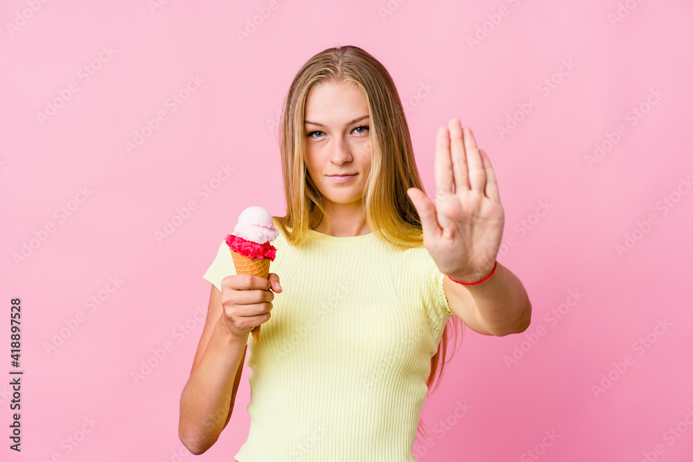 Young russian woman eating an ice cream isolated standing with outstretched hand showing stop sign, preventing you.