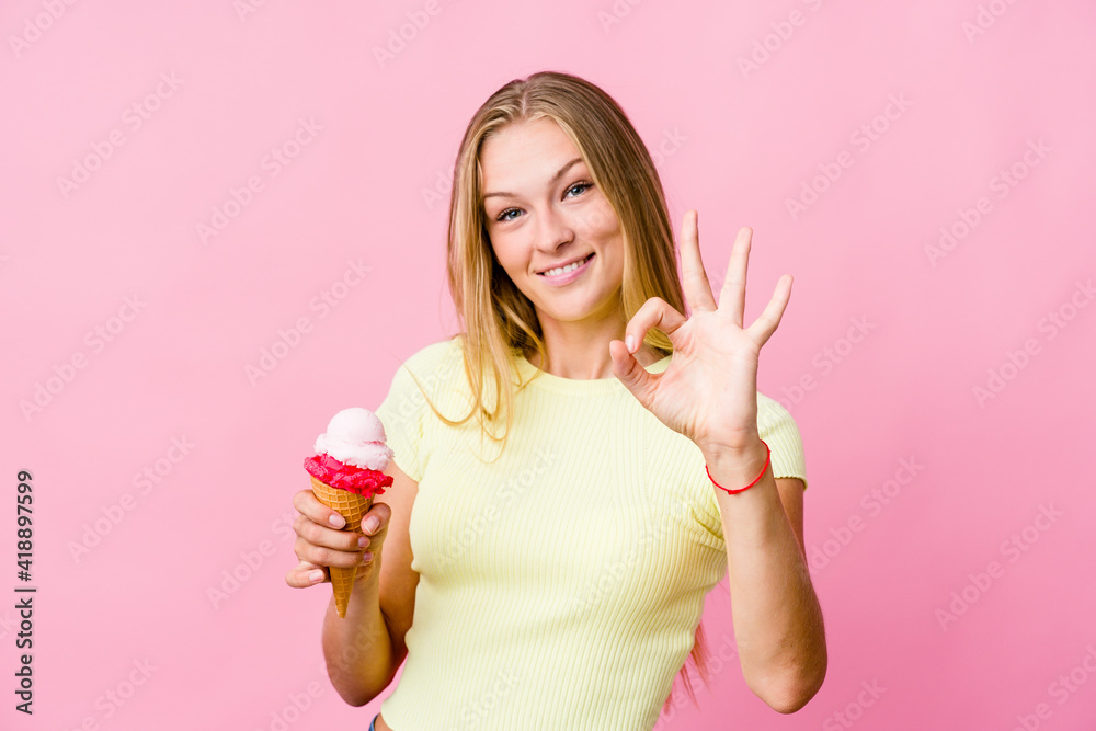 Young russian woman eating an ice cream isolated cheerful and confident showing ok gesture. Young russian woman eating an ice cream isolated cheerful and confident showing ok gesture.