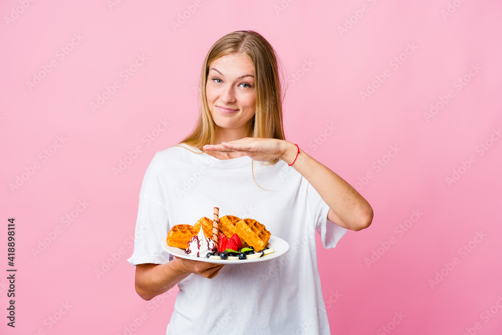 Young russian woman eating a waffle isolated holding something with both hands, product presentation. Young russian woman eating a waffle isolated holding something with both hands, product presentation.