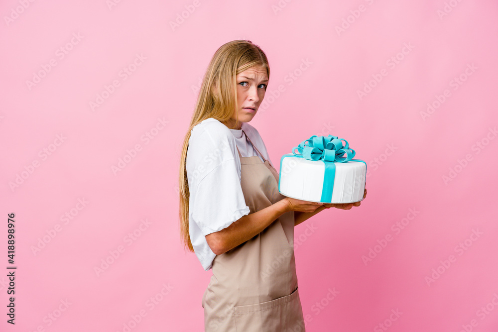Young russian baker woman holding a delicious cake scared and afraid. Young russian baker woman holding a delicious cake scared and afraid.
