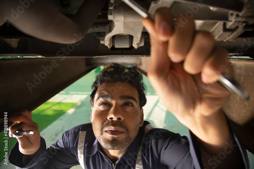 Car mechanic working under a vehicle at workshop 