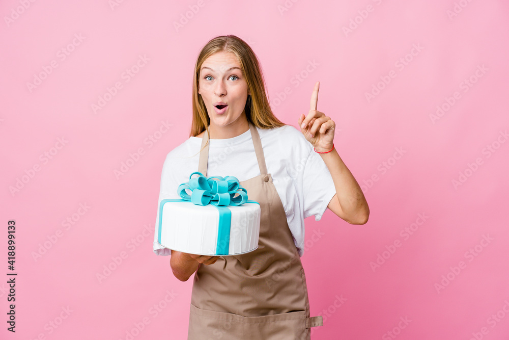 Young russian baker woman holding a delicious cake having an idea, inspiration concept. Young russian baker woman holding a delicious cake having an idea, inspiration concept.