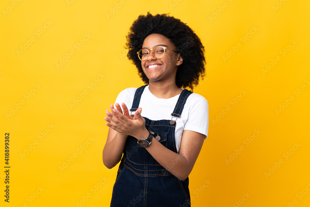 Young African American woman isolated on yellow background applauding after presentation in a conference Young African American woman isolated on yellow background applauding after presentation in a conference