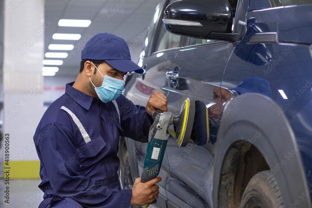 mechanic polishing a car with an electric orbital polisher in auto repair Shop mechanic polishing a car with an electric orbital polisher in auto repair Shop