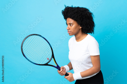 Young African American woman isolated on blue background playing tennis