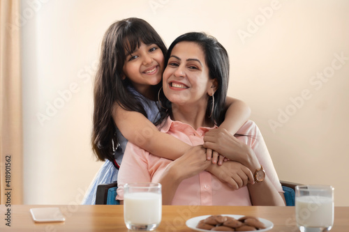 A HAPPY DAUGHTER AND MOTHER POSING TOGETHER IN FRONT OF CAMERA	