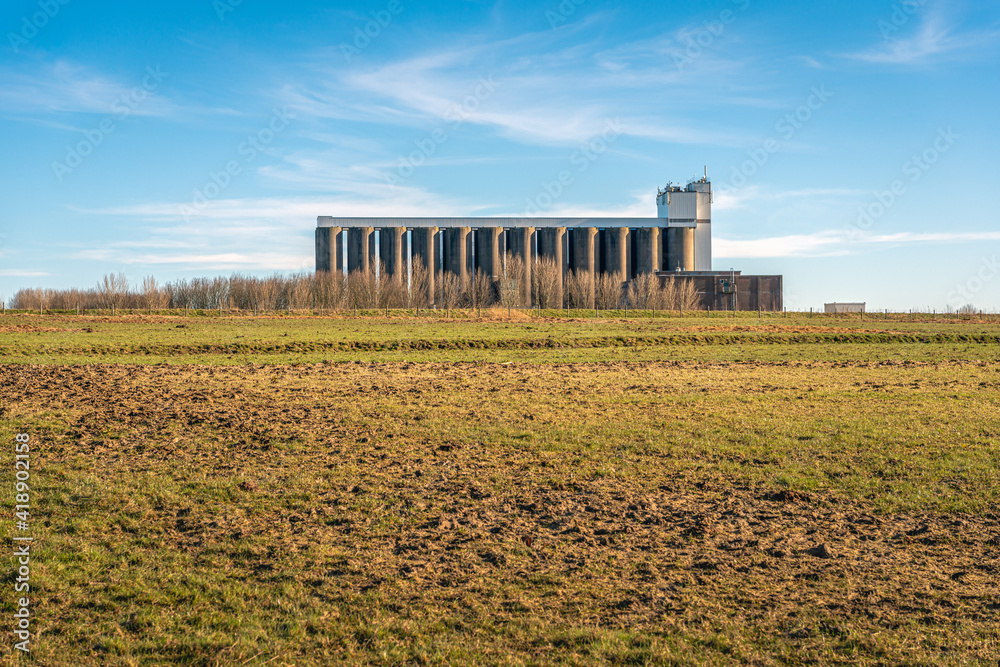 Large storage silos of an animal feed company on the edge of an agricultural area. The photo was taken on a sunny day in the winter season.
