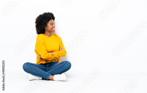 Young African American woman sitting on the floor in lateral position © luismolinero