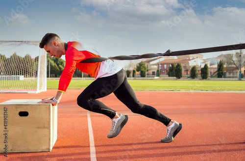 A young man trains power output in athletics with an elastic band