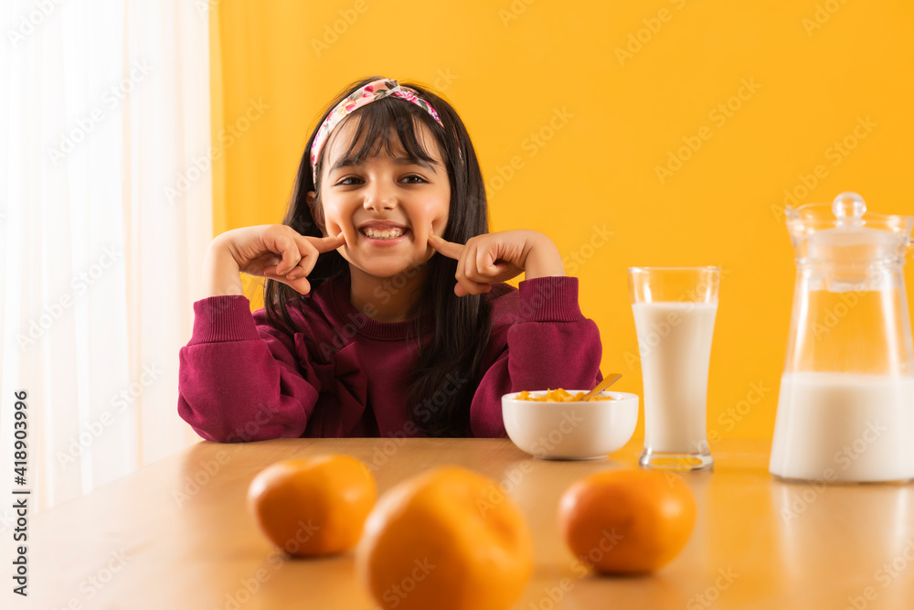 A HAPPY KID PLAYFULLY SITTING ON TABLE DURING BREAKFAST A HAPPY KID PLAYFULLY SITTING ON TABLE DURING BREAKFAST