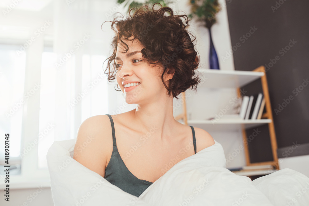 Pleased girl wrapping in white blanket while enjoying her lazy day at home Pleased girl wrapping in white blanket while enjoying her lazy day at home