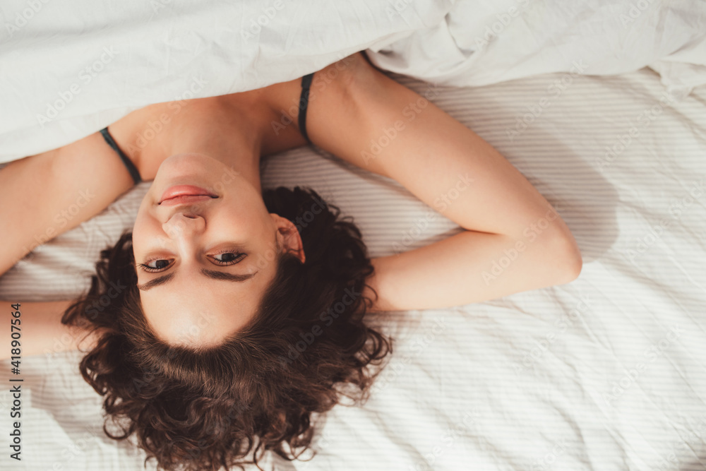 Girl lying on her bed covered with white blanket while spending time at home Girl lying on her bed covered with white blanket while spending time at home