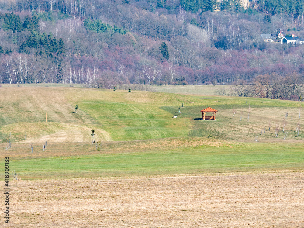 Obraz premium Resort golf course in the valley with bright green grass and naked leafless trees