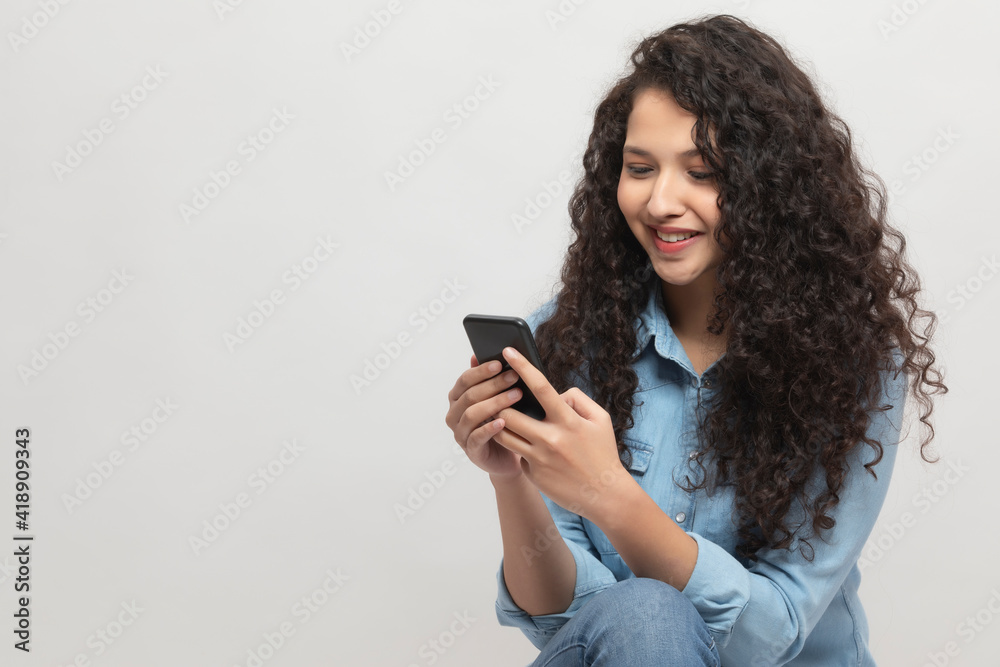 A TEENAGER HAPPILY SITTING AND USING MOBILE PHONE A TEENAGER HAPPILY SITTING AND USING MOBILE PHONE