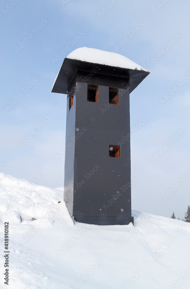 close-up view of brick stone pipe covered with metal sheets and black smoke box on snowy roof at winter close-up view of brick stone pipe covered with metal sheets and black smoke box on snowy roof at winter