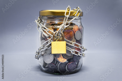 Jar full of coins locked with chain  savings concept