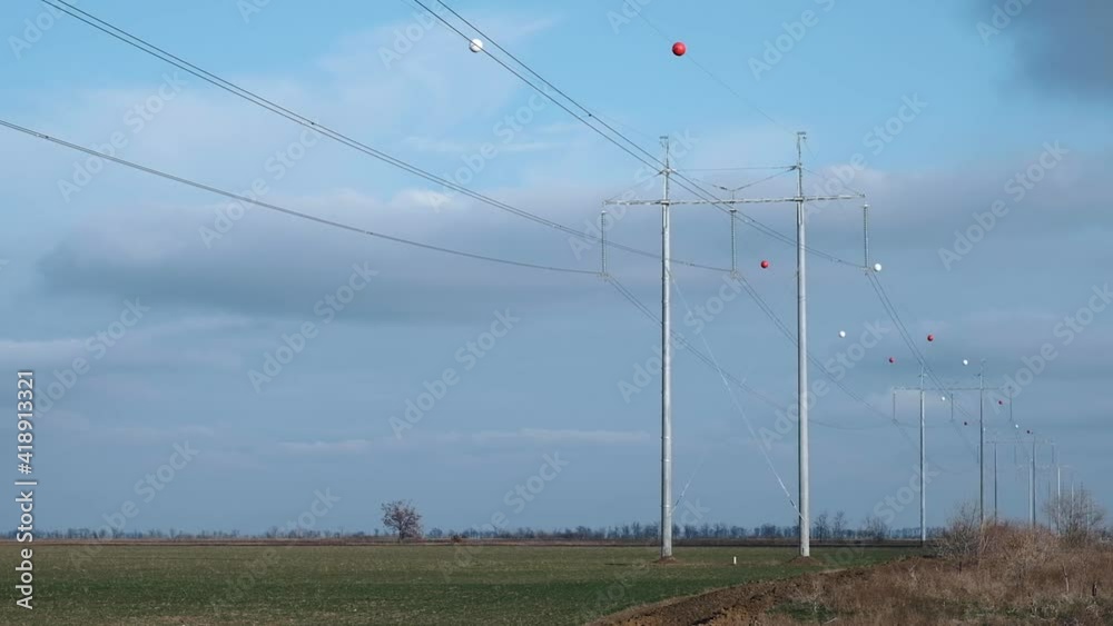 Marker balls mounted on high voltage power lines. Marker balloons help make power lines more visible to low-flying aircraft and are also designed to keep birds away.