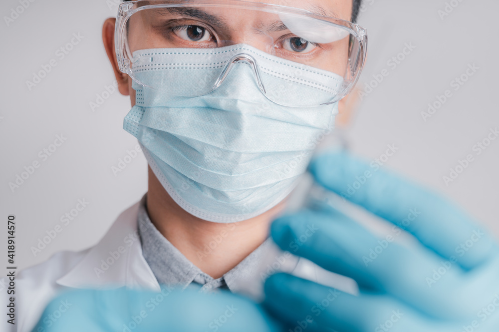 Doctors wear a surgical mask and glasses, Scientists, Scientists hold syringes and vaccines for COVID-19., vaccination and laboratory experiments. Virus protection concept COVID-19, Doctors wear a surgical mask and glasses, Scientists, Scientists hold syringes and vaccines for COVID-19., vaccination and laboratory experiments. Virus protection concept COVID-19,