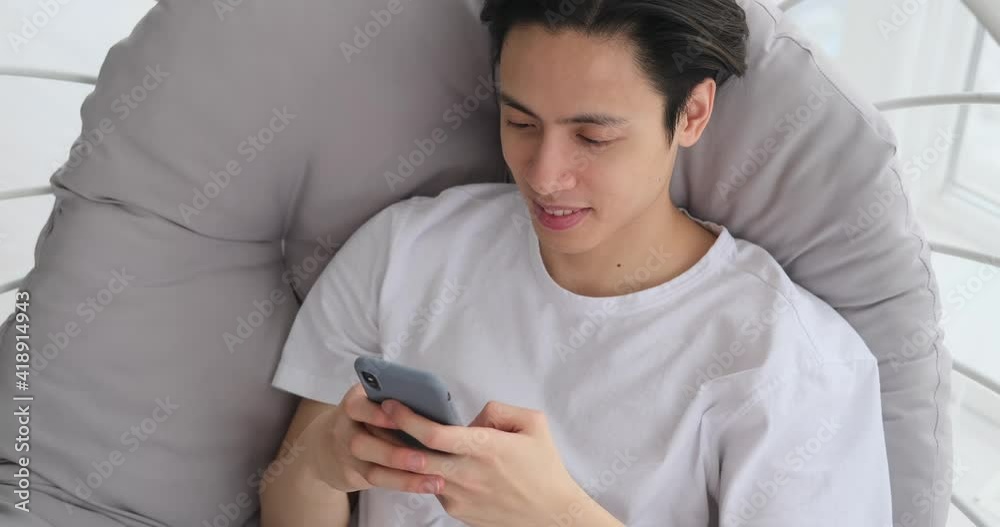 Man smiling and text messaging on mobile phone sitting on luxury chair