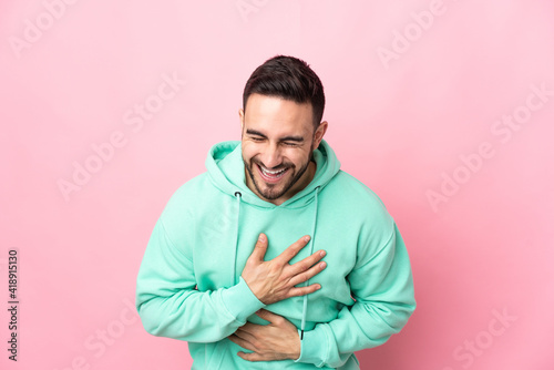 Young caucasian handsome man isolated on pink background smiling a lot © luismolinero