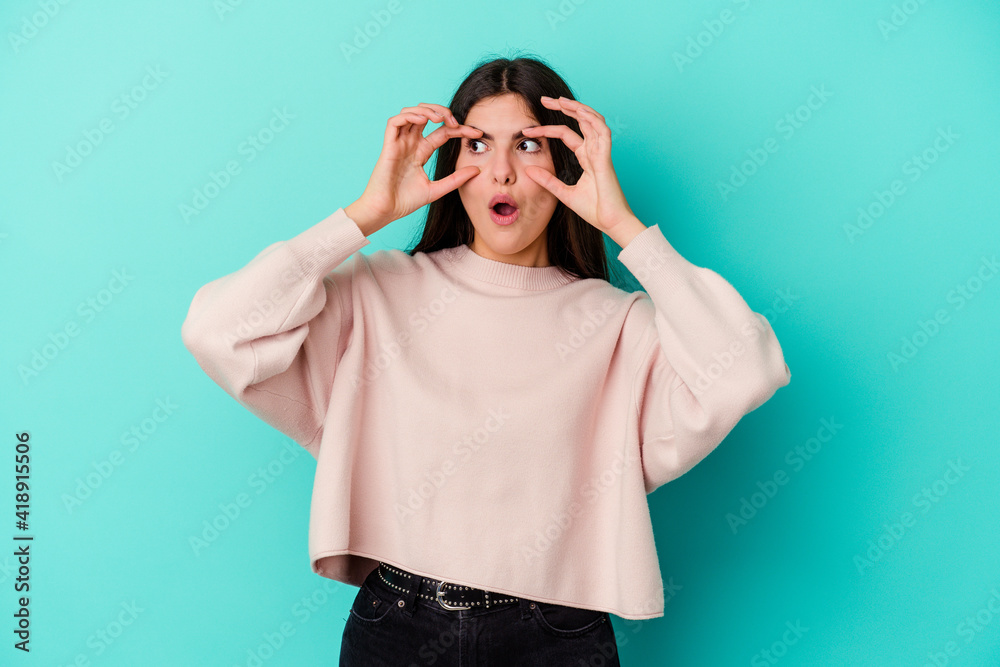 Young caucasian woman isolated on blue background keeping eyes opened to find a success opportunity. Young caucasian woman isolated on blue background keeping eyes opened to find a success opportunity.