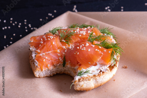 baked bun, oiled with fresh cream, garnished with smoked fish trout and sprinkled with fresh dill and sesame seeds on parchment paper