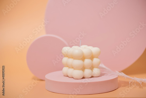 A trendy pink soy cube bubble candle on a pink podium