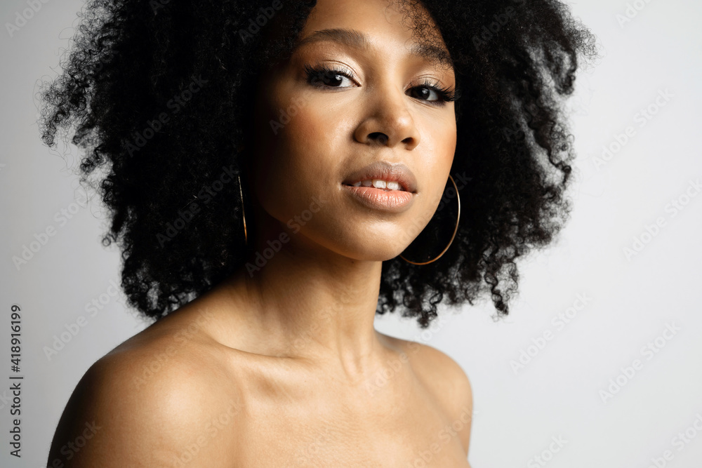 Portrait of a female model of Afro appearance. Black hair is curly. Photo shoot in a photo studio on a white background. copy space. Beautiful smooth facial skin. Portrait of a female model of Afro appearance. Black hair is curly. Photo shoot in a photo studio on a white background. copy space. Beautiful smooth facial skin.