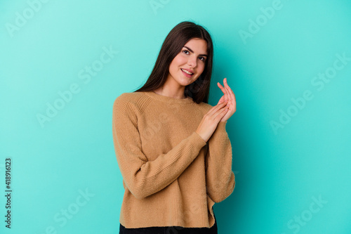 Young caucasian woman isolated on blue background feeling energetic and comfortable, rubbing hands confident.