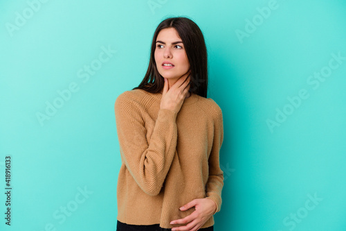 Young caucasian woman isolated on blue background suffers pain in throat due a virus or infection.