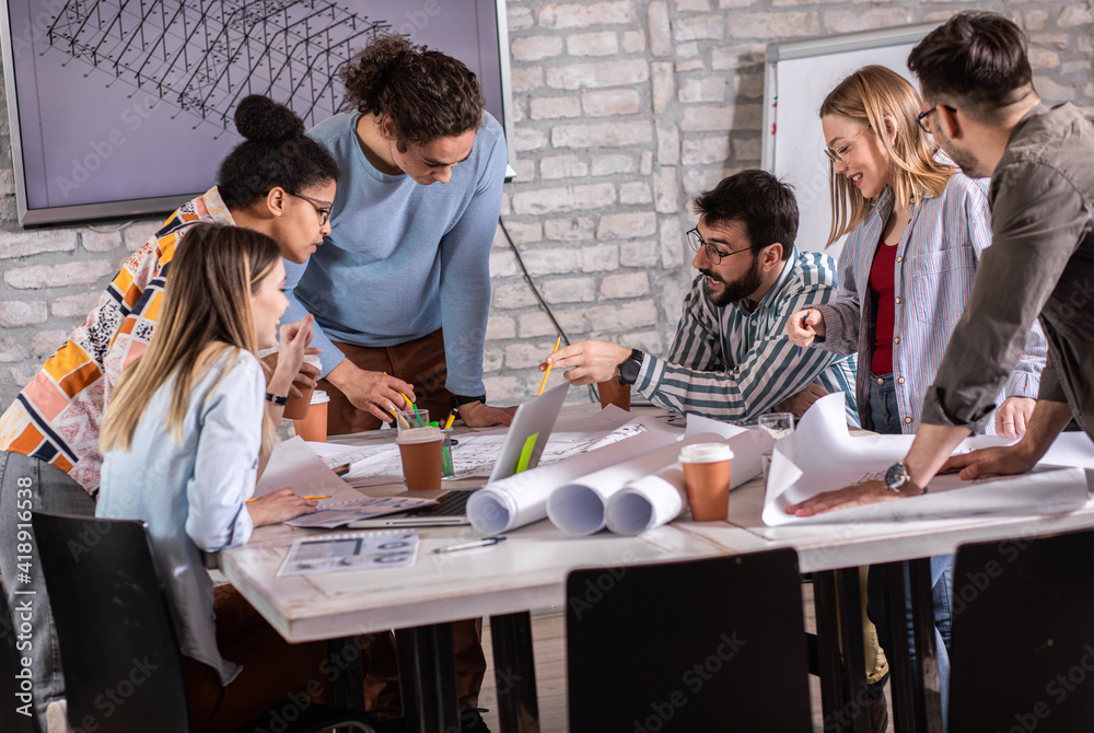 Group of young people discussing architectural designs in the creative office.