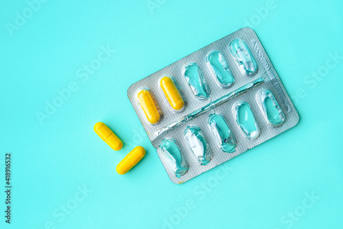 Half empty blister pack with yellow pills on light blue background