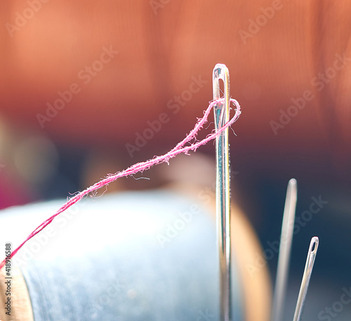 a needle and thread sticking out against the background of spools © Igor