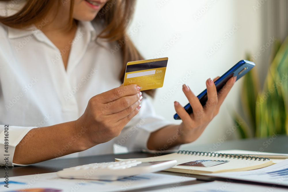 woman holding credit card and using smartphone at home. Businessman or entrepreneur working in office. Online shopping, internet banking, store online, payment, spending money, e-commerce concept. woman holding credit card and using smartphone at home. Businessman or entrepreneur working in office. Online shopping, internet banking, store online, payment, spending money, e-commerce concept.