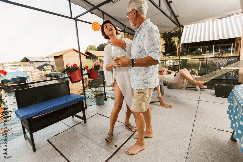 Fototapeta premium Senior couple dancing on a party outside drinking wine.