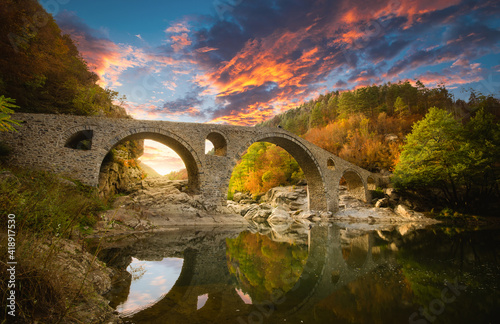 Devil's bridge at Ardino, Bulgaria. Ancient stone bridge at autumn forest at sunset. Ottoman Architecture near the town of Ardino, Rhodope Mountains and Arda river, Kardzhali Region