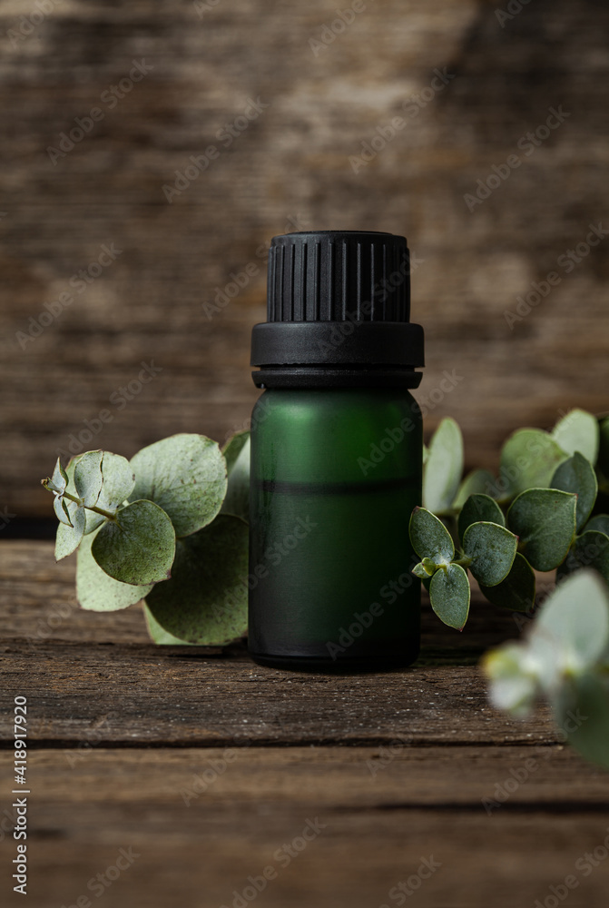 Eucalyptus essential oil and fresh eucalyptus leaves on wood background. Eucalyptus essential oil and fresh eucalyptus leaves on wood background.