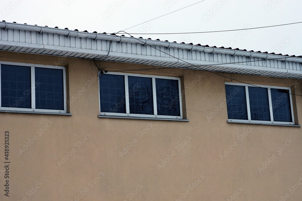 a row of three small windows on a brown concrete wall of a building under a white roof