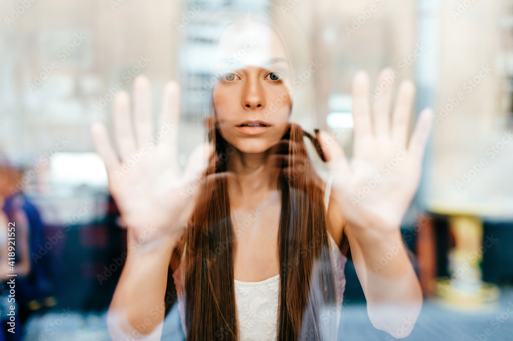 Portrait of young beautiful romantic brunette girl with long hair posing behind glass
