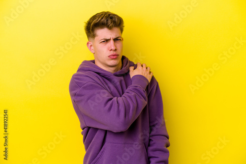 Young caucasian man isolated on yellow background having a shoulder pain. © Asier