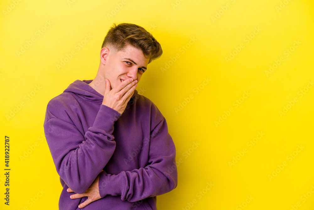 Young caucasian man isolated on yellow background laughing happy, carefree, natural emotion.