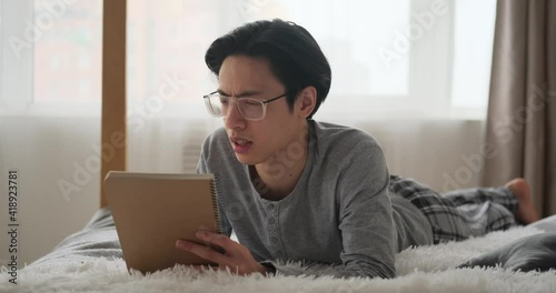 Man writing to do list in notepad on bed at home photo