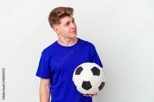Young caucasian man playing soccer isolated on background dreaming of achieving goals and purposes